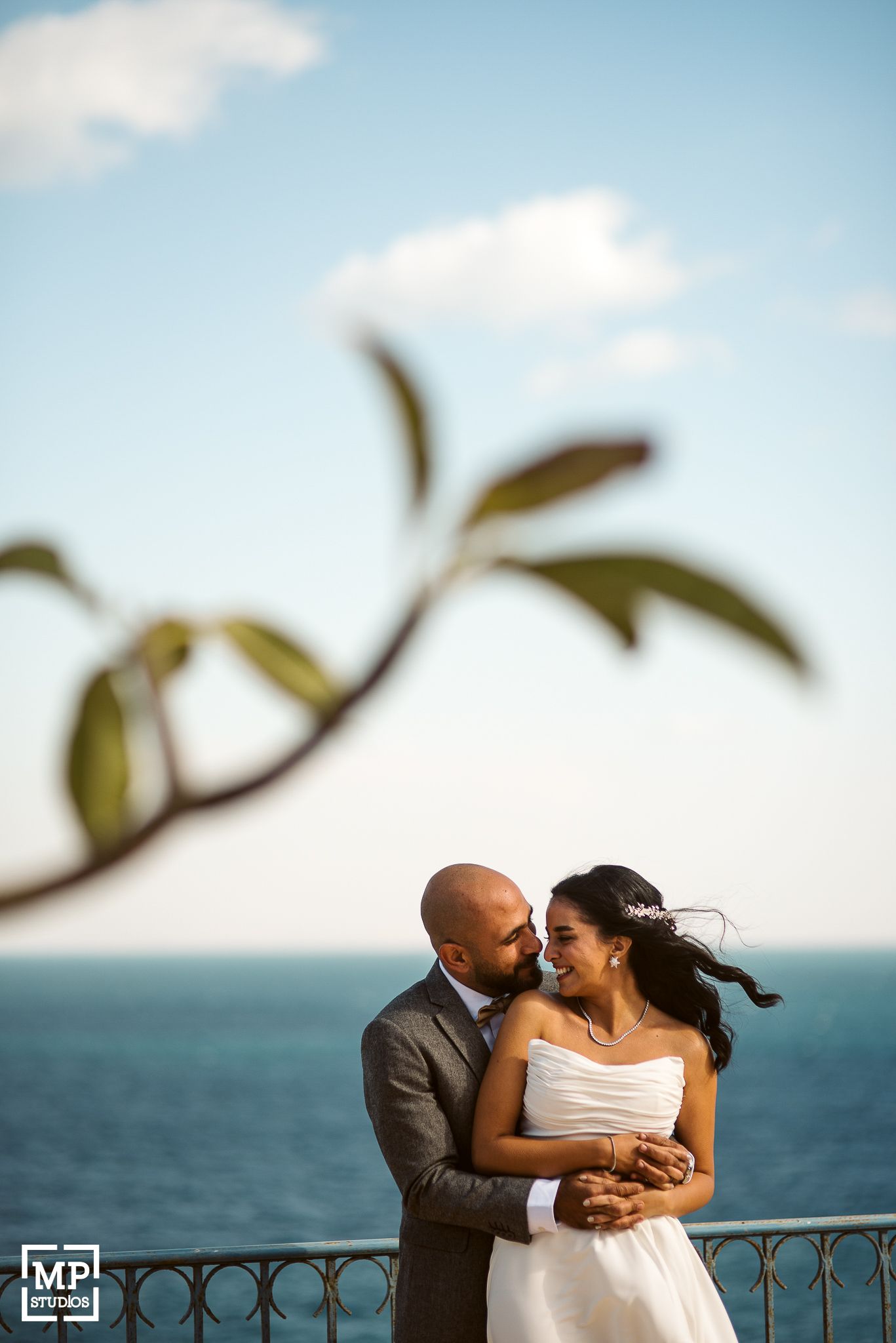 A couple shares an intimate oceanside moment during their wedding photoshoot.
