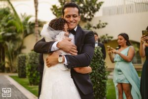 An emotional embrace between newlyweds while wedding guests capture the moment on phones.