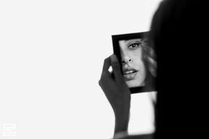 Artistic black and white reflection portrait using mirror fragment against white background.
