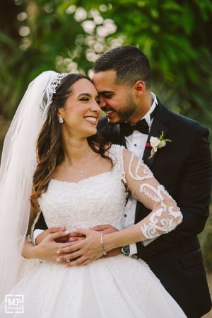 Intimate wedding portrait of newlyweds sharing a joyful moment in a garden setting.