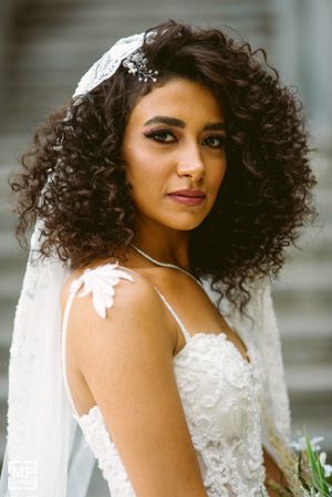 Beautiful bridal portrait showcasing curly hair, delicate veil and lace wedding dress details.