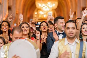 Joyful wedding reception crowd dancing and celebrating with raised hands.