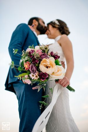 Romantic wedding photo featuring stunning bouquet with peach and burgundy flowers.