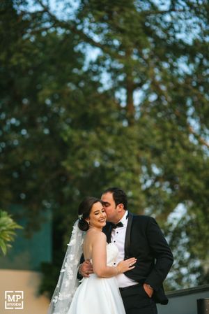 Intimate wedding portrait of couple embracing outdoors with greenery in background.