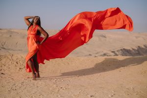 Flowing orange fabric billows in desert wind creating dramatic movement against sand dunes.