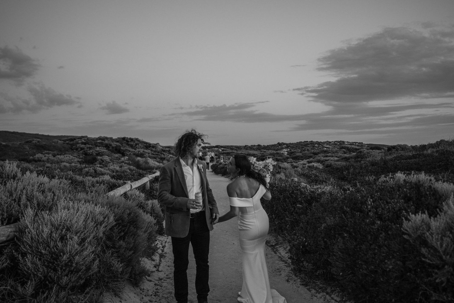 Couple walking hand in hand along a scenic path at dusk.