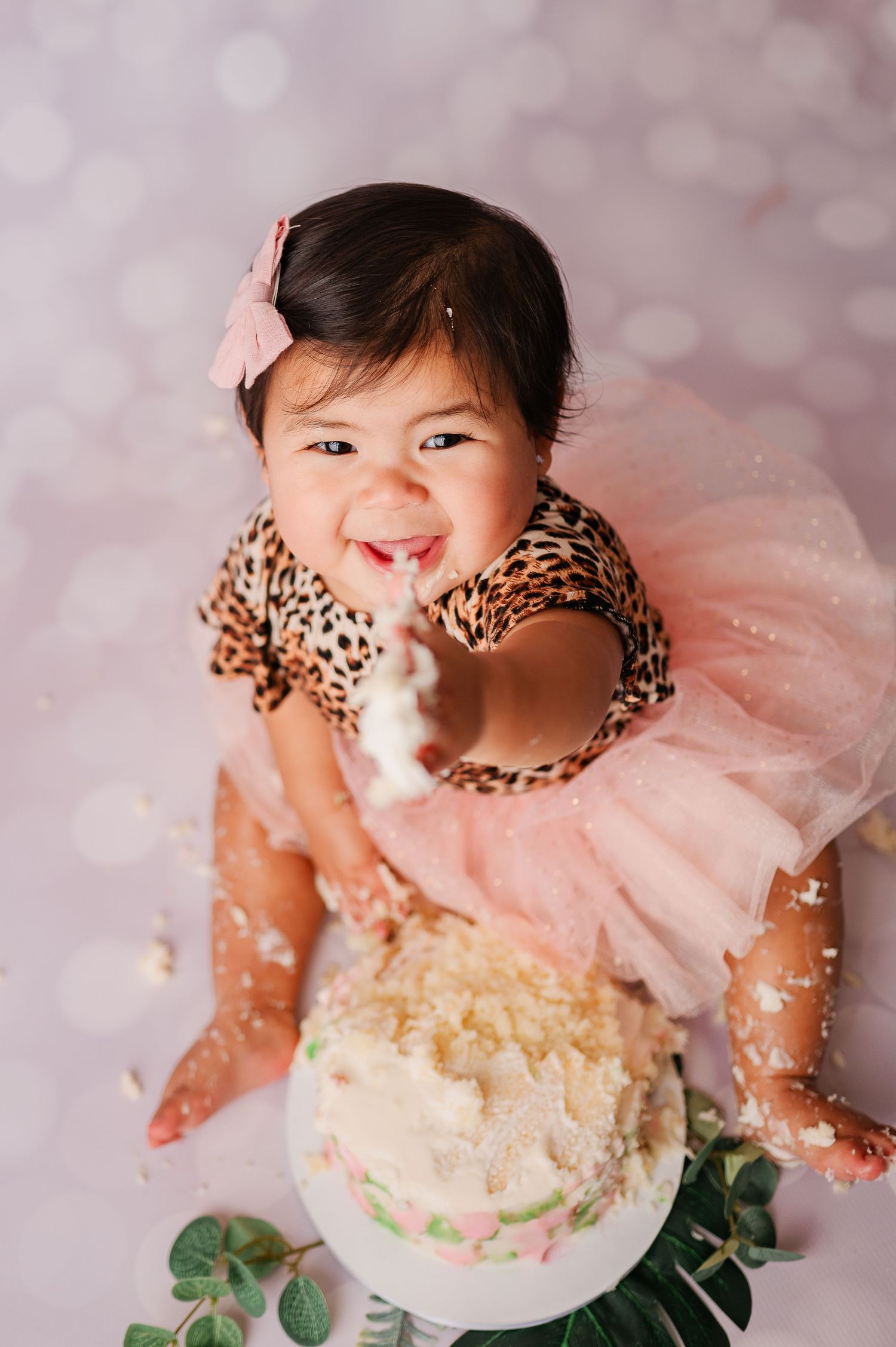 one year old sharing cake with photographer during cake smash photoshoot
