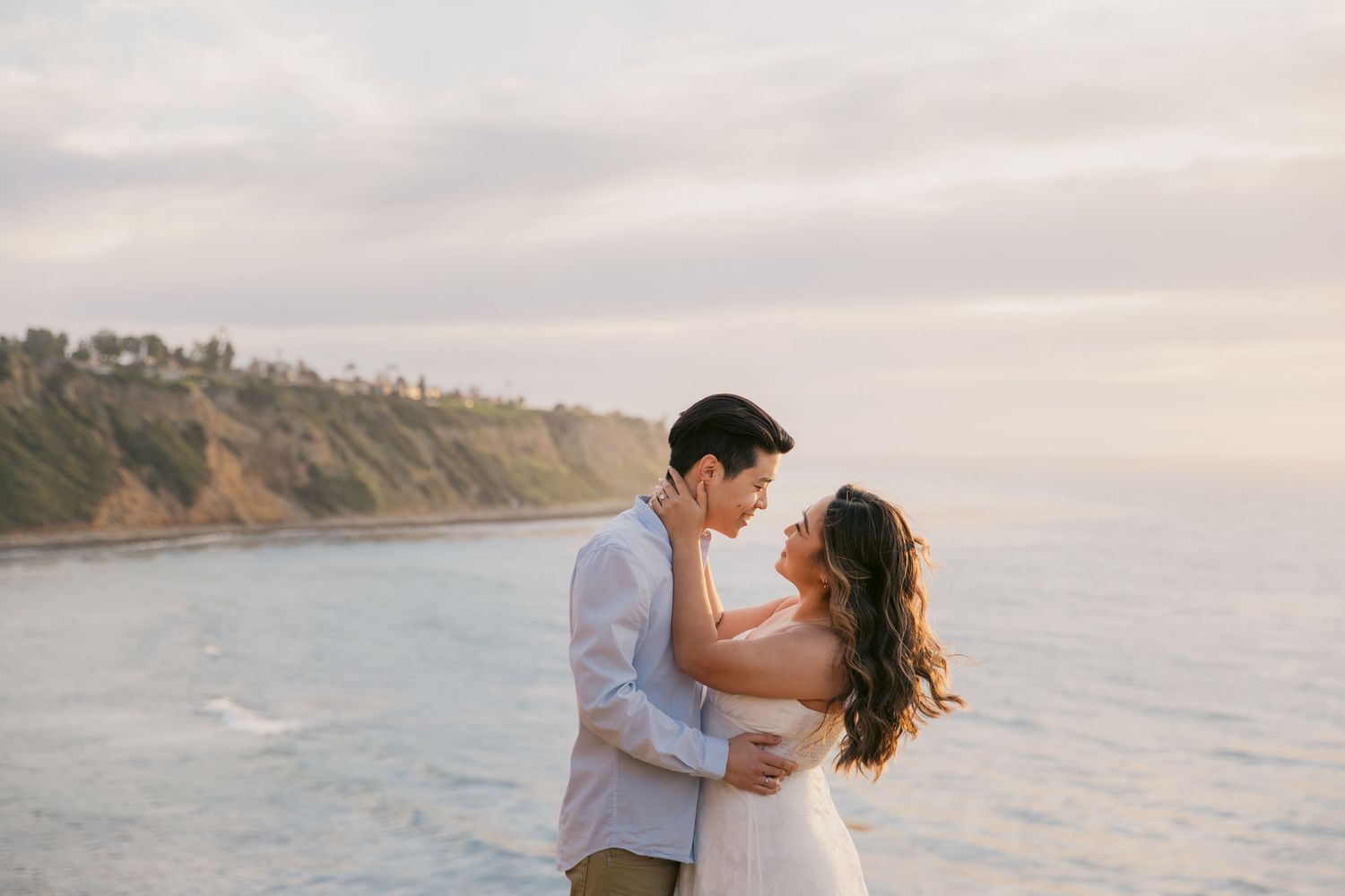 Romantic beachside engagement session at sunset with ocean views.
