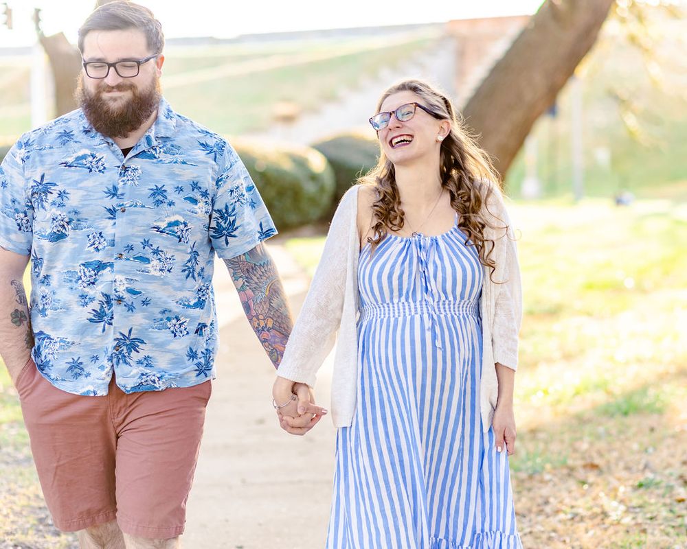 Couple walking together outdoors, wearing blue floral and striped outfits in a sunny natural setting.