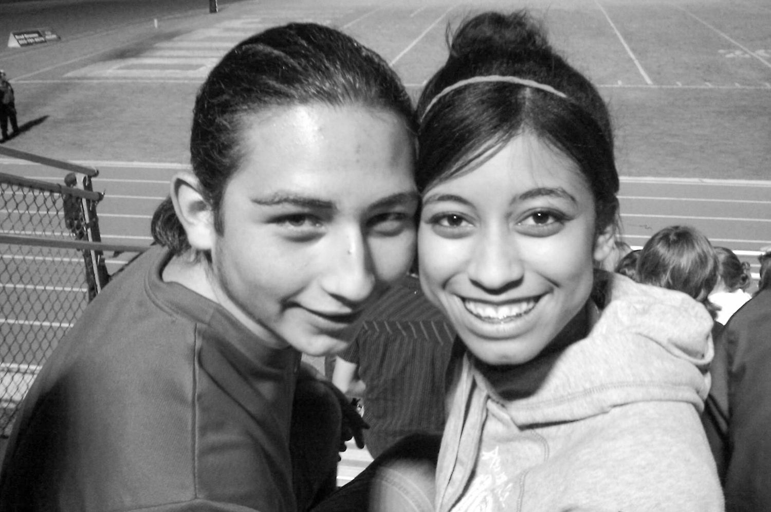 Black and white portrait of two friends smiling together at an outdoor event.