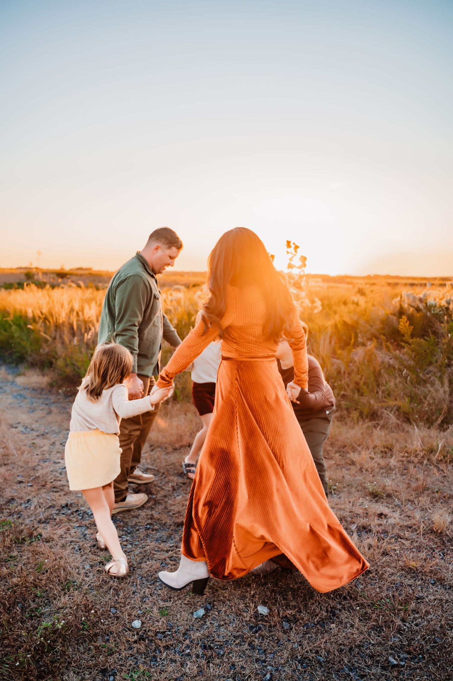 Young family holding hands and twirling in circle in Staten Island, NY