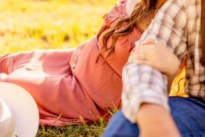 Close-up view of a maternity photo session in a sun-drenched meadow.