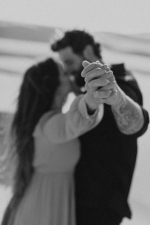 Black and white photo of couple dancing, focusing on their clasped hands.