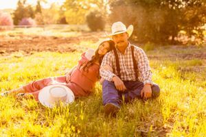 A romantic country maternity photoshoot in a golden sunlit field at sunset.
