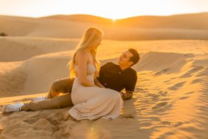 Romantic couple relaxing on desert sand during golden hour.