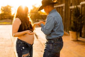 Couple sharing intimate moment during sunset by wooden barn.