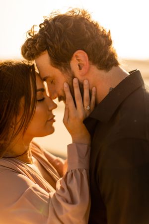 Intimate close-up of couple sharing tender moment in warm sunset light.