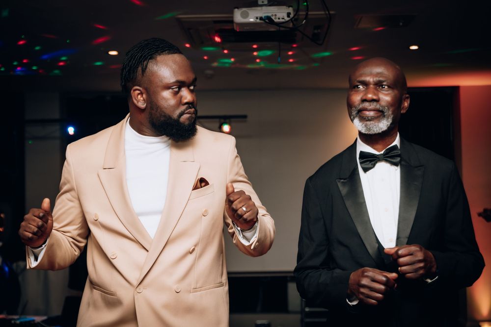 Two men in formal suits standing and socializing at an indoor event.
