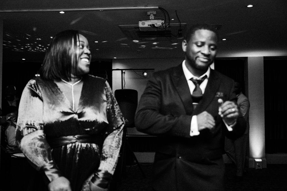 Party guests sharing laughter and dancing at a black-tie celebration.