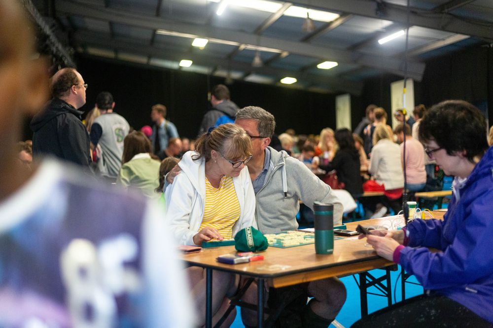 People gathered around tables participating in an indoor community event or workshop.