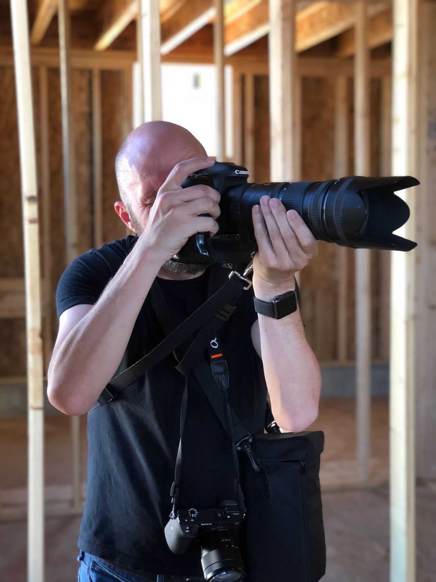 Photographer with telephoto lens taking pictures in wooden framed interior.