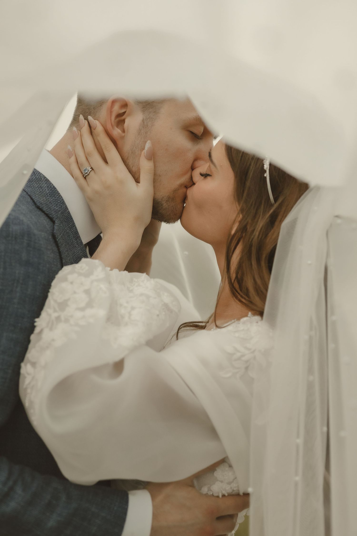 a bride and groom kissing under the brides veil