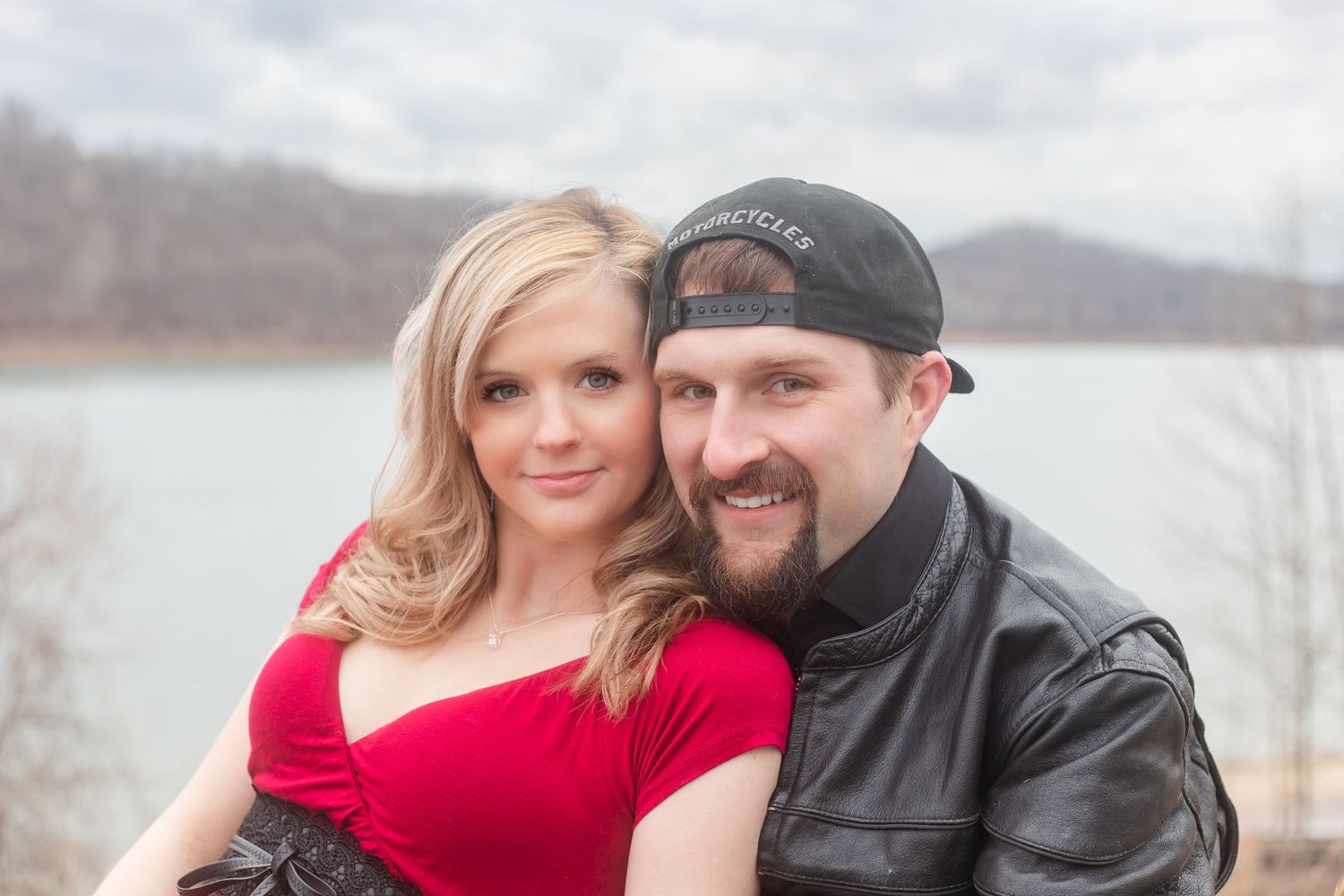 A couple shares an intimate moment by a lake during their winter photoshoot.