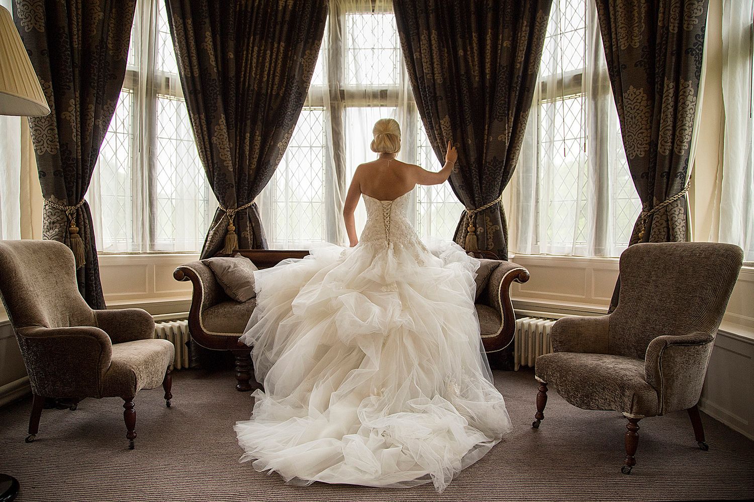 beautiful dress on bride who is looking out of bridal suite window at Rothley court hotel
