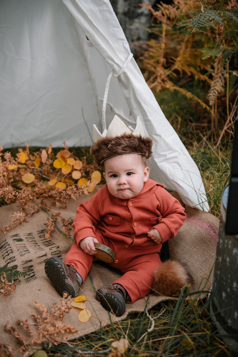 Rustic outdoor setting with teepee and wooden decor in an autumn birch forest.