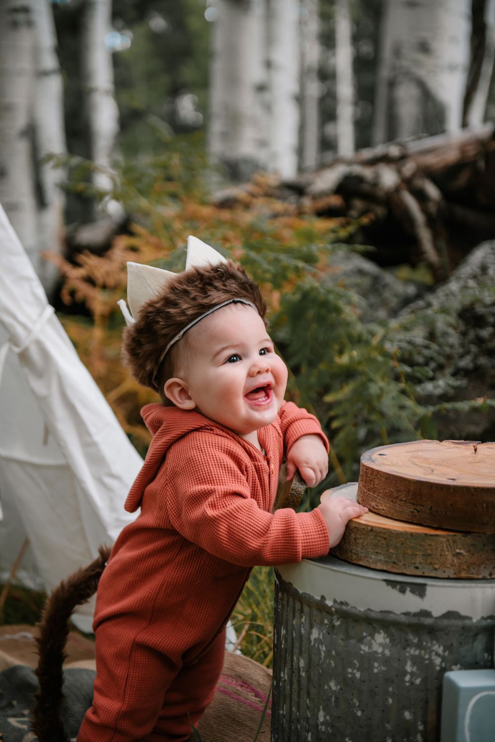 A playful moment captured in a forest setting with autumn leaves and white teepees in the background.