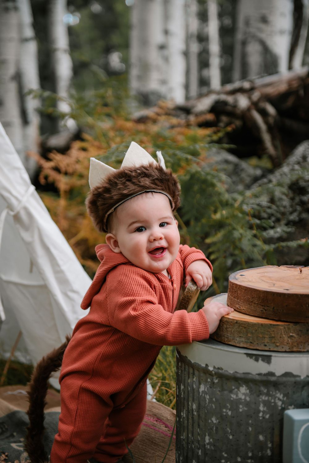 A joyful outdoor photo session among aspen trees with decorative props and a white teepee.