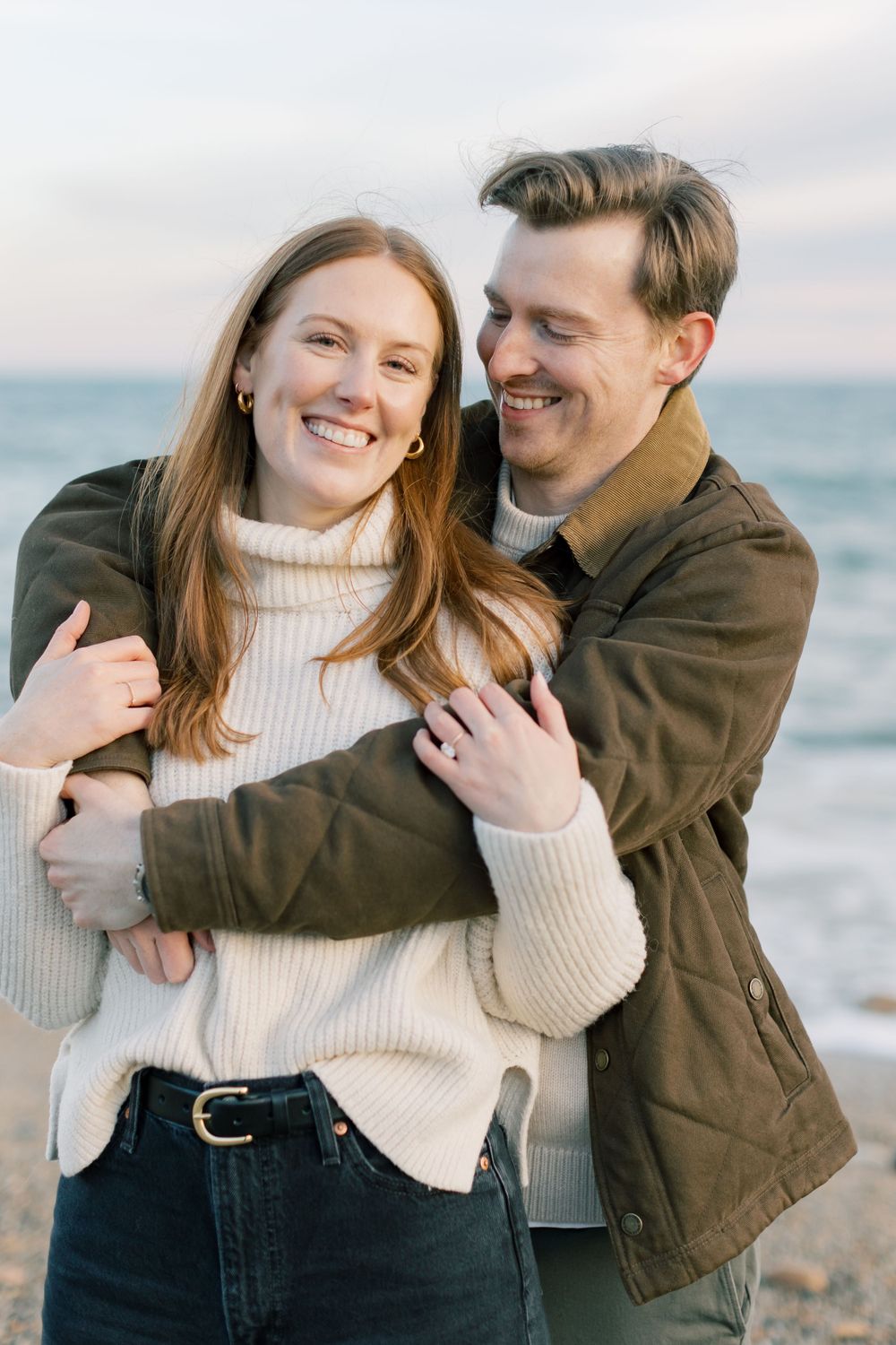 A joyful embrace on a beach with ocean waves in the background in Montauk, Long Island, New York.
