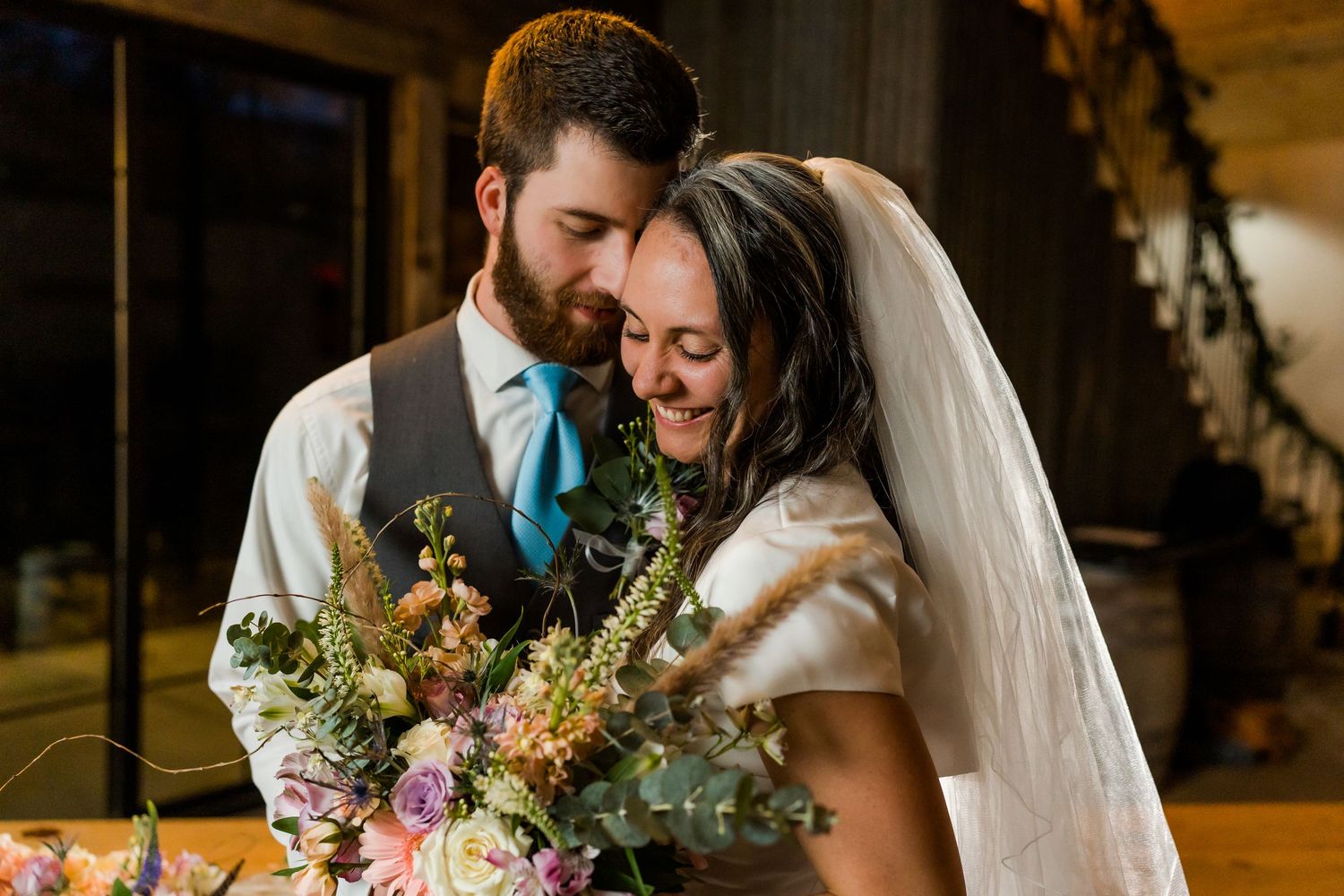 bride and groom nuzzle while holding the bouquet of flowers
