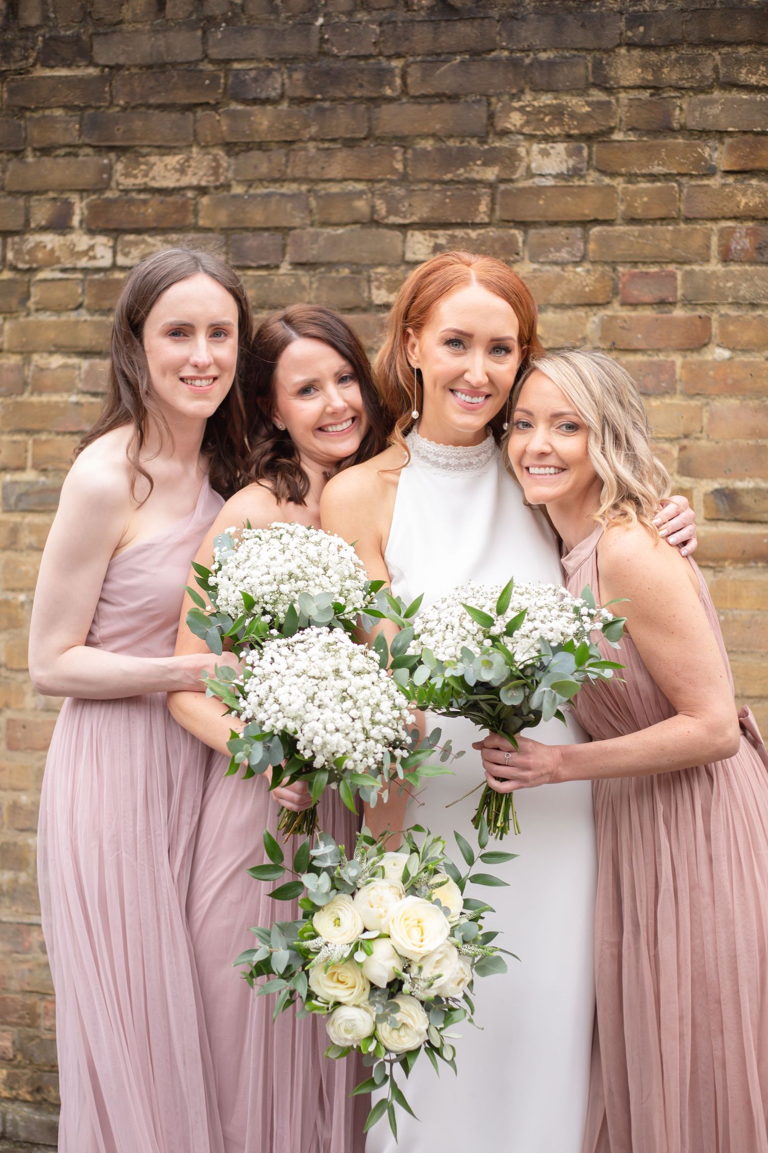bride and bridesmaids smiling at camera with their flowers