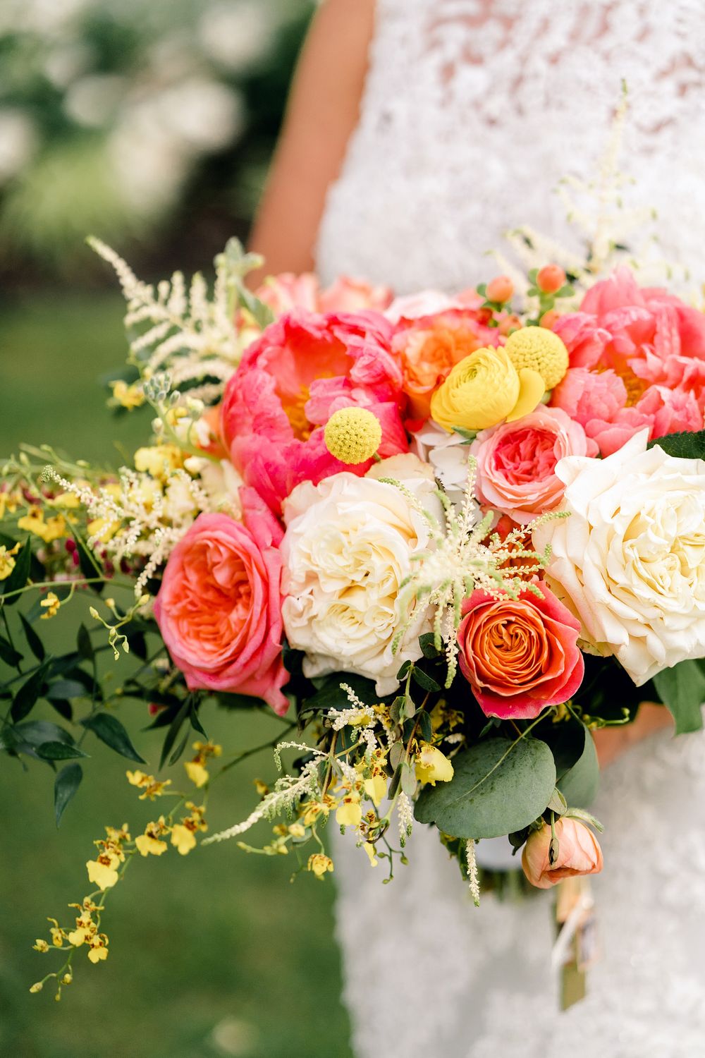 A stunning coral and cream wedding bouquet with roses, peonies and delicate greenery.