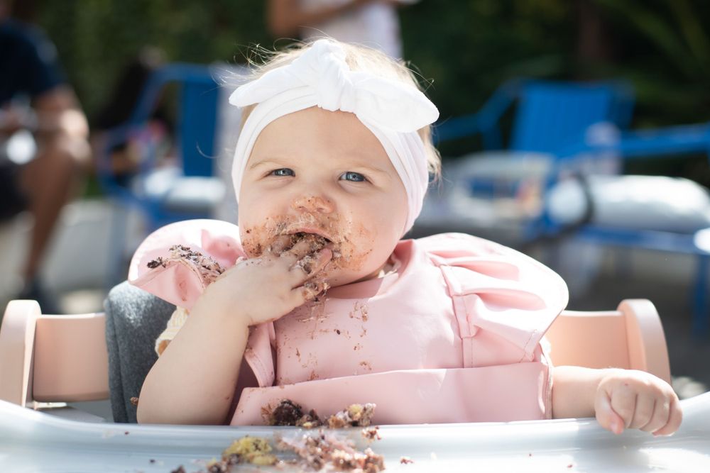 Gorgeous girl enjoying her first birthday cake.