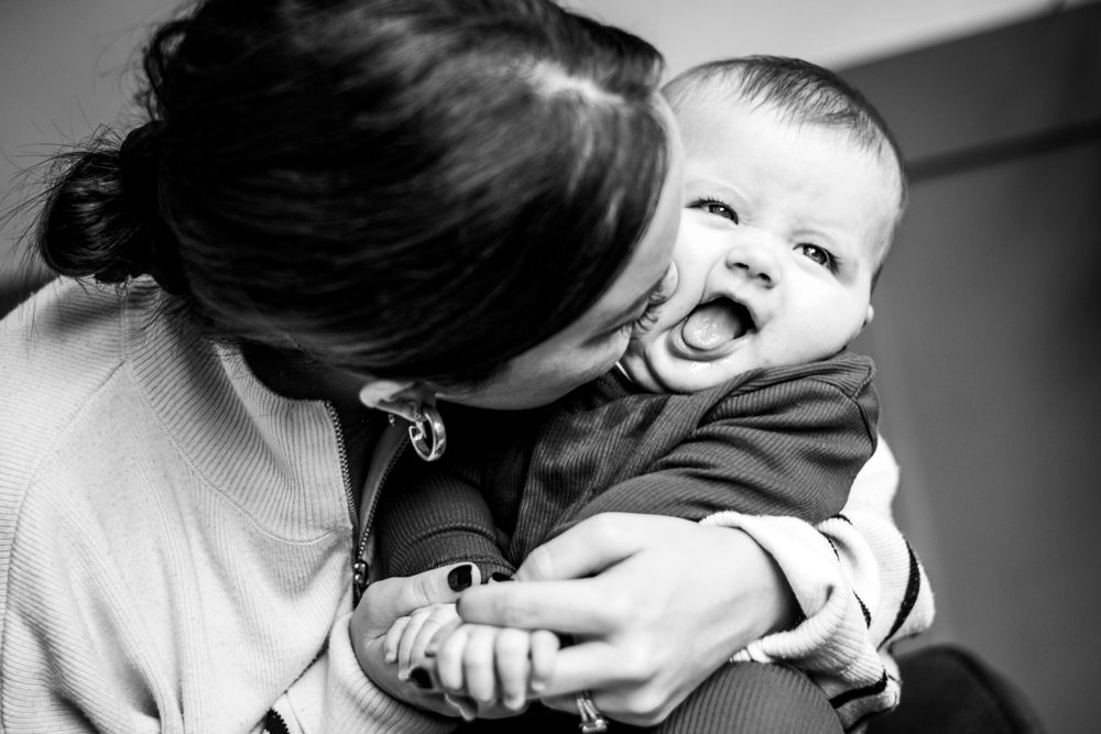 Mummy and daughter kisses during a newborn photoshoot, at home in Leatherhead