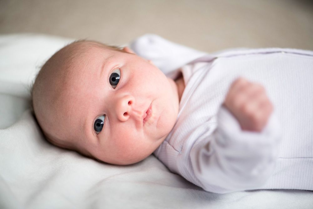 3 week old baby girl's big blue eyes during a newborn photoshoot, Surrey.