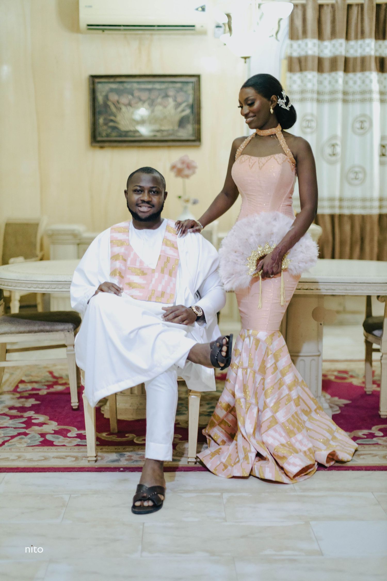 A formal portrait in a living room with pink and white traditional wedding attire.