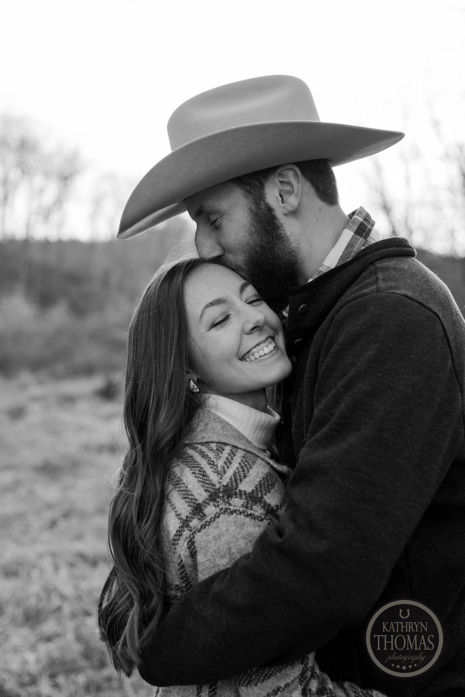 Black and white portrait of a couple sharing an intimate embrace outdoors.
