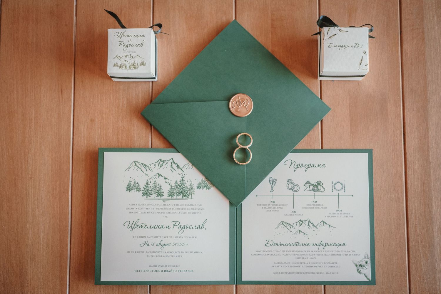 Elegant green wedding invitation suite with gold rings on wooden background.