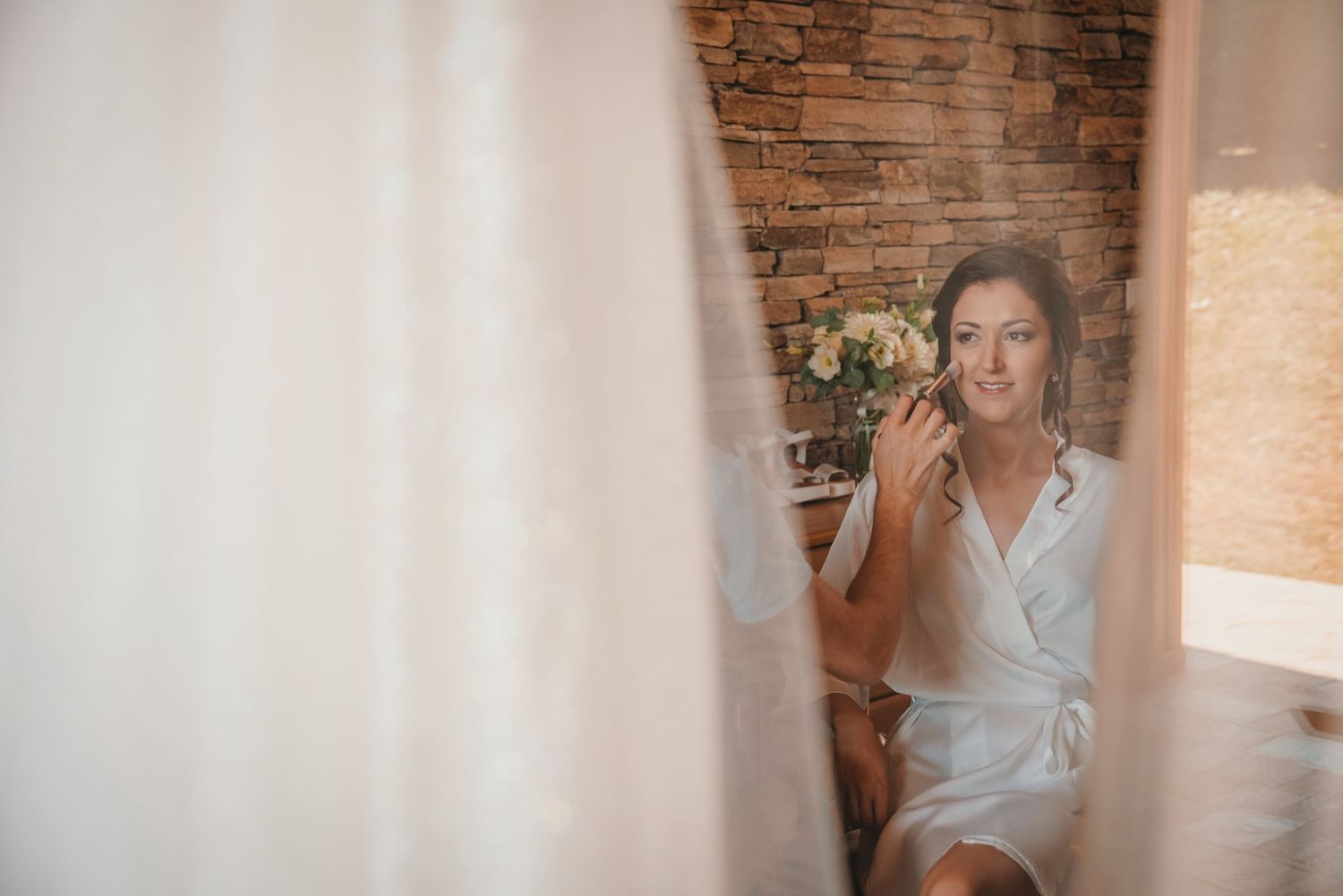 Getting ready scene with white dress reflection in mirror against brick wall.