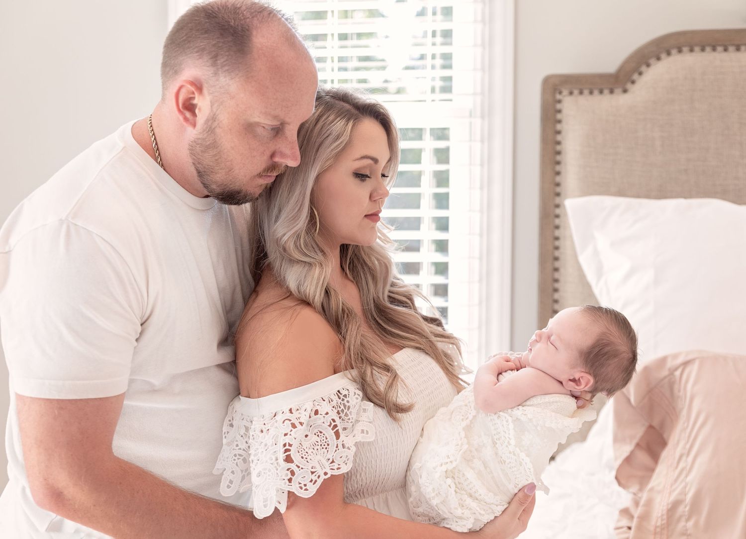 Family moment in bright bedroom with white decor and natural lighting.