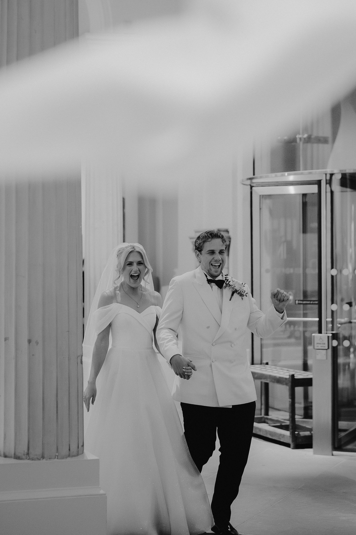 bride and groom cheering as they enter the grand sculpture gallery at the Ashmolean Museum in Oxford