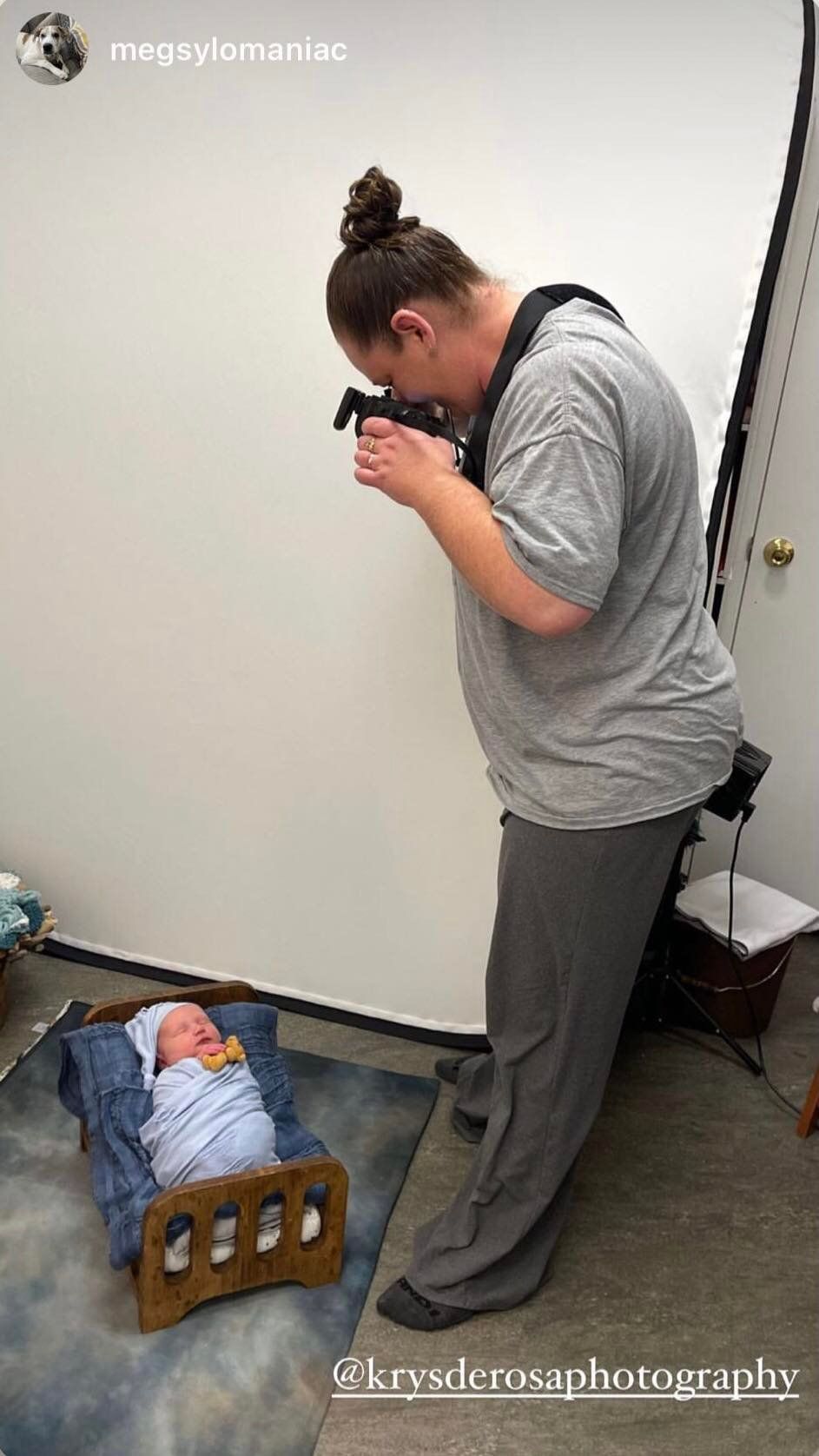 Behind-the-scenes photo of photographer at work capturing overhead shot of baby on denim backdrop.