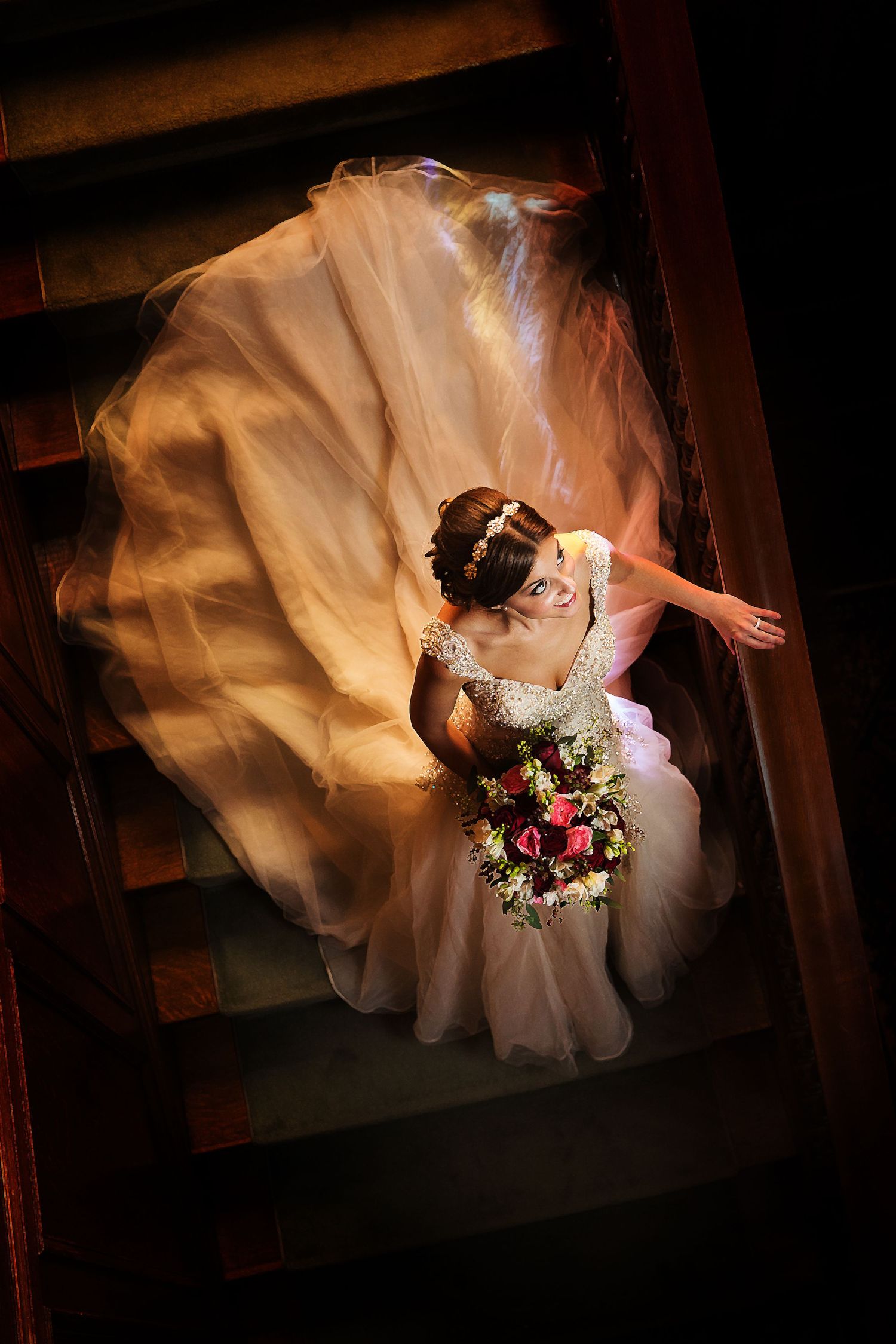 Dramatic overhead shot of a flowing wedding gown captured in moody lighting.