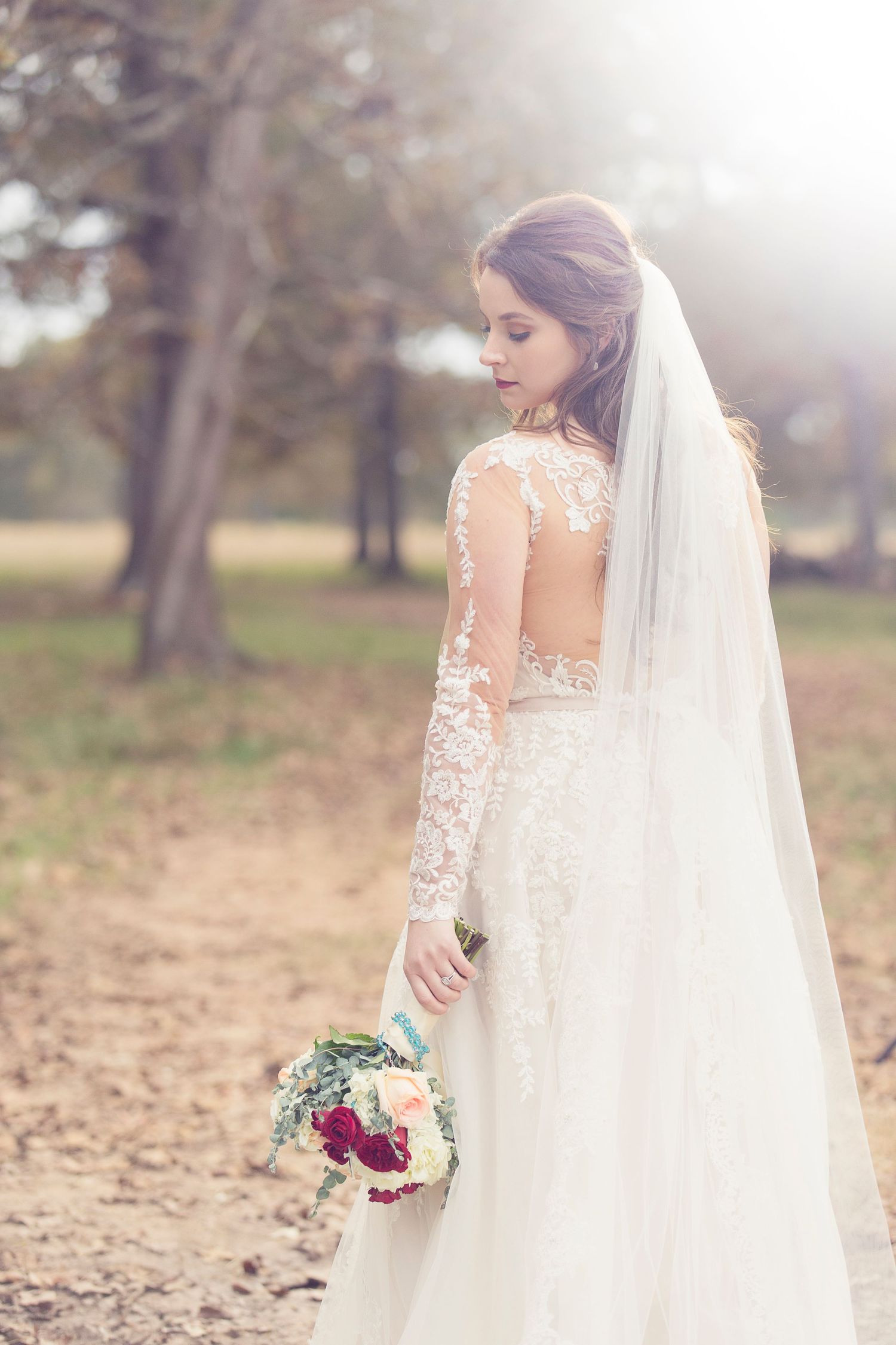 Ethereal outdoor bridal portraits capture flowing lace details and a dramatic veil in natural sunlight.