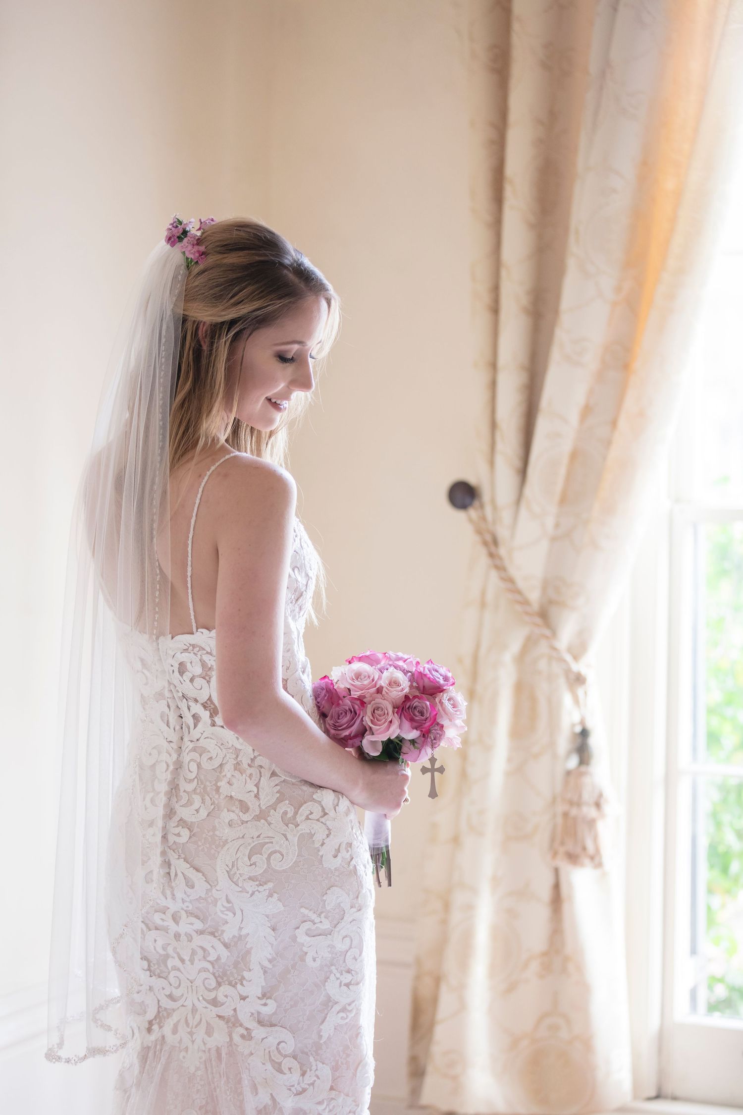 Dreamy window-lit bridal portraits highlight delicate lace details and soft pink roses.