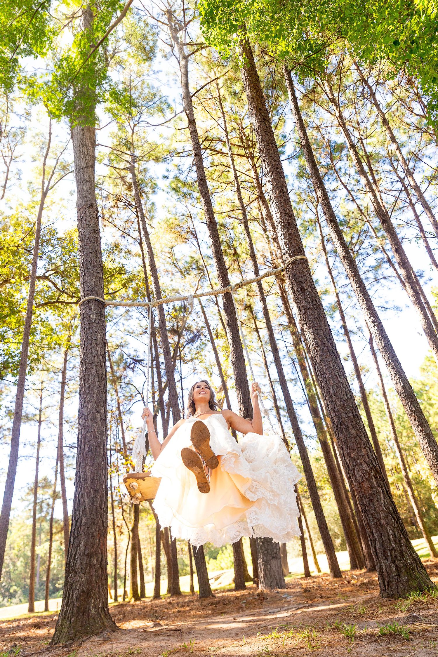 Ethereal outdoor photo with flowing white dresses against sunlit pine trees.