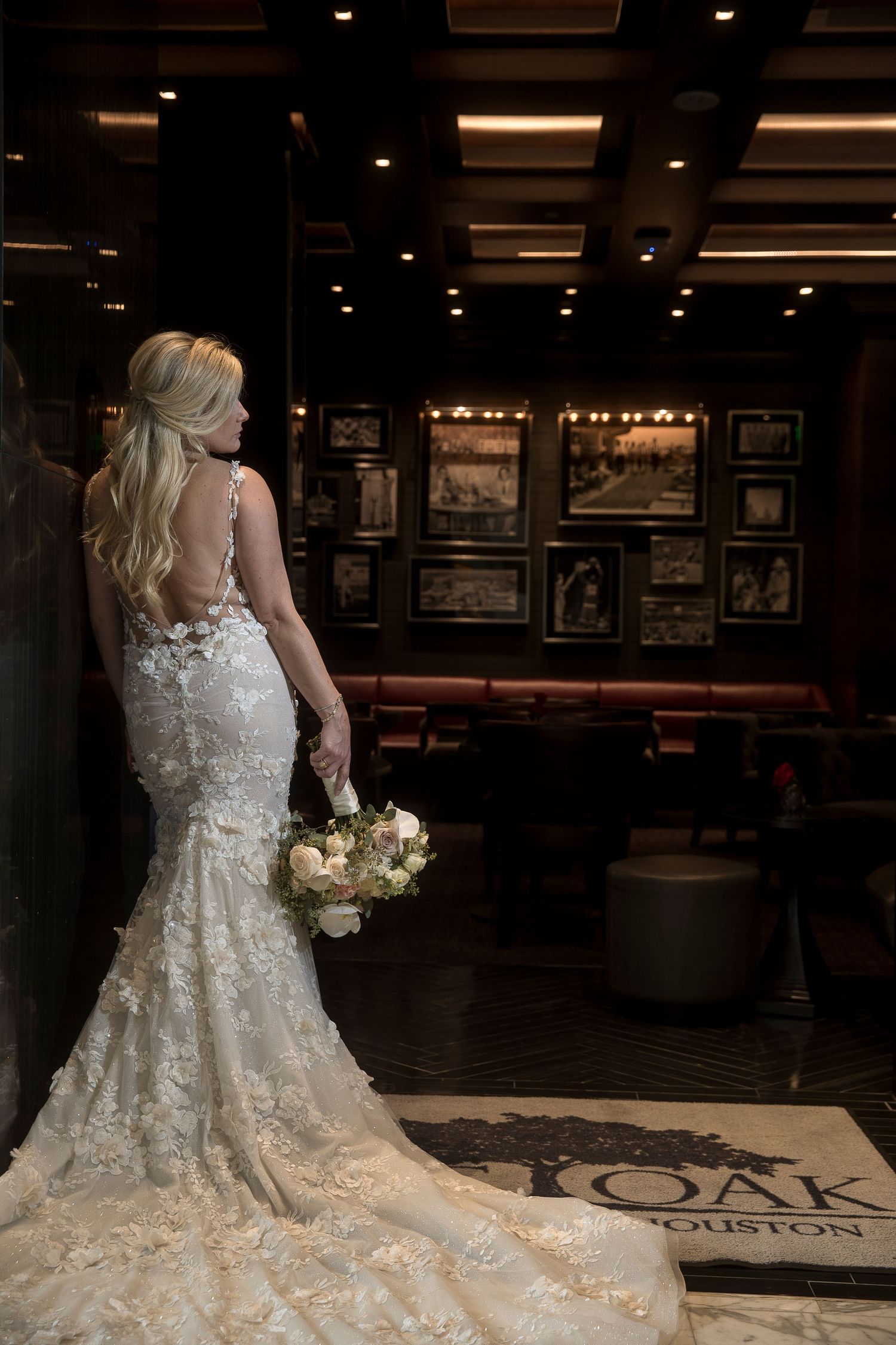 An elegant white lace wedding gown is displayed in a dimly lit restaurant setting.